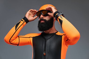 Yakın çekim turuncu neopren dalgıç elbisesi ve gri arka plan üzerinde izole dalış maske sakallı bir erkek portresi.