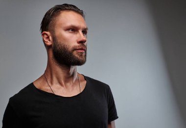 Sakal ve saç modeli tarafına seyir siyah t-shirt ile yakışıklı bir erkek.