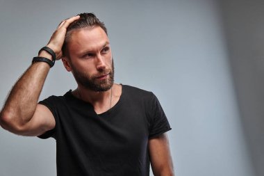 Sakal ve saç modeli tarafına seyir siyah t-shirt ile yakışıklı bir erkek.