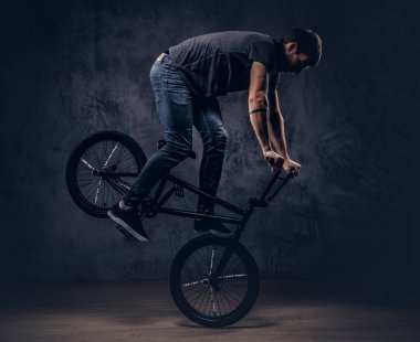 Yakışıklı adam t-shirt ve jeans içinde Bmx ile akrobatik bir figür bir stüdyoda yapar..