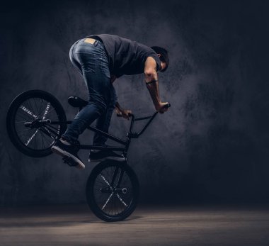 Yakışıklı adam t-shirt ve jeans içinde Bmx ile akrobatik bir figür bir stüdyoda yapar..