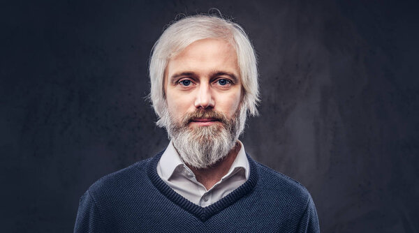 Portrait of a thoughtful aged male with a gray hair and beard isolated on a dark background.