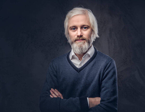 Portrait of a handsome mature male with a gray beard isolated on a dark background.
