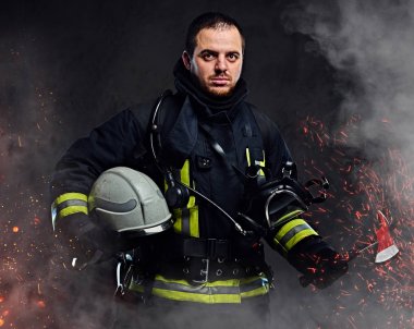 Profesyonel bir itfaiyeci karanlık bir arka plan üzerinde düzgün güvenlik kask yangında kıvılcım holding ve duman giymiş.