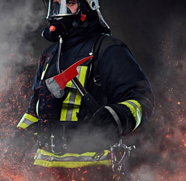 Bir itfaiyeci üniforma ve oksijen maskesi giymiş bir kırmızı balta ayakta yangında kıvılcım ve karanlık bir arka plan üzerinde duman tutar.