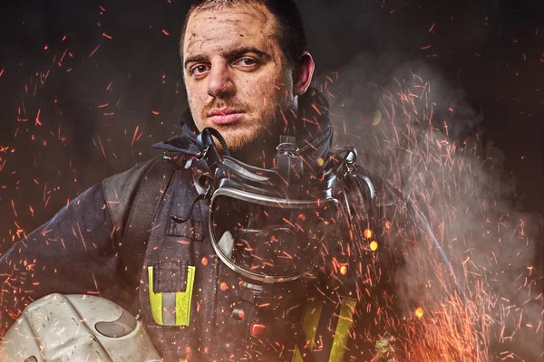 プロの消防士に身を包んだ火花火の安全ヘルメットを保持している均一かつ煙黒っぽい背景に — ストック写真
