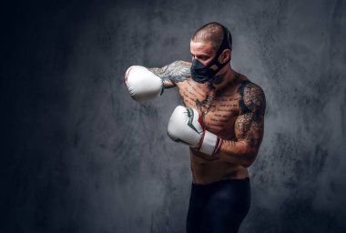 Stüdyo portre gömleksiz, dövme maskeli savaşçı erkek gri vignette arka plan üzerinde.