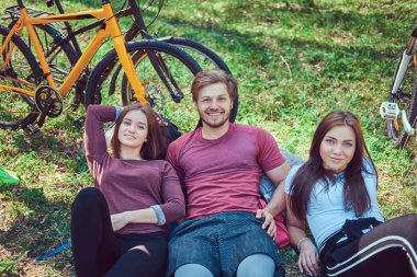 Arkadaş grubu zemin relax ve konuşma birlikte parkta bisikleti sonra oturuyor. Dostluk kavramı.