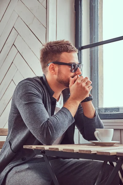 サングラスとカジュアルでハンサムな若い男服のコーヒー ショップでコーヒーを飲む — ストック写真