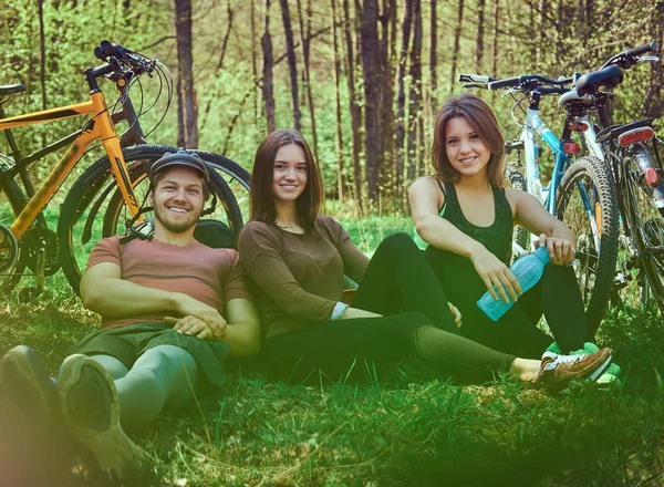 Arkadaş grubu zemin relax ve konuşma birlikte parkta bisikleti sonra oturuyor. Dostluk kavramı.