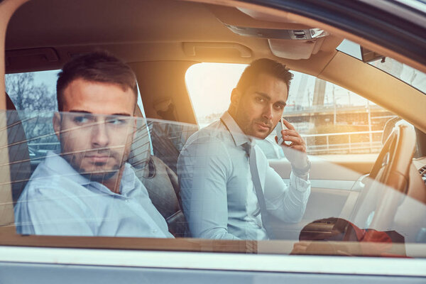 A handsome stylish businessman and his driver in a car.