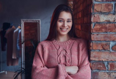 Şık elbise çatı iç ile bir odada bir tuğla duvara yaslanmış iken gülümseyen güzel şirin esmer portresi giymiş.