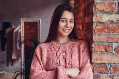 Şık elbise çatı iç ile bir odada bir tuğla duvara yaslanmış iken gülümseyen güzel şirin esmer portresi giymiş.