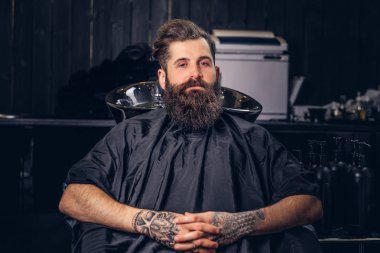 Kollarını bir kuaför salonu saç yıkama önce bir dövme ile yakışıklı sakallı erkek.