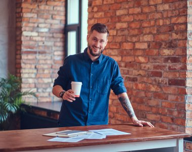 Onun kol ayakta çatı iç ile bir odada bir dövme ile mutlu yakışıklı erkek.