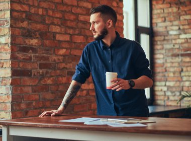 Onun kol ayakta çatı iç ile bir odada bir dövme ile mutlu yakışıklı erkek.