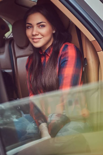 Portrait of a Caucasian woman in a flannel shirt sitting in the car.