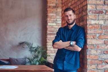 Onun kol ayakta çatı iç ile bir odada bir dövme ile mutlu yakışıklı erkek.