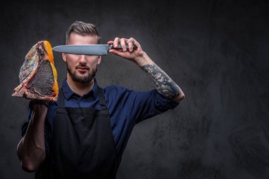 Profesyonel kasap bıçağı ve büyük bir parça çiğ füme et tutar