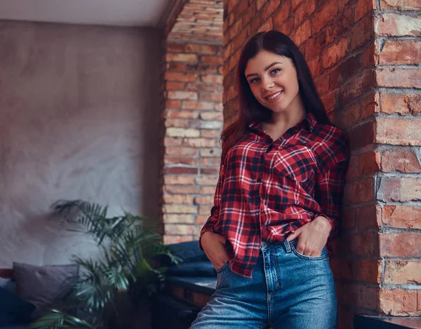 Portrait of a sexy brunette in a flannel shirt and jeans