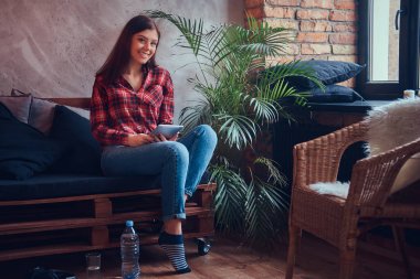 Pazen tişört ve kot bir kanepede oturan sevimli esmer