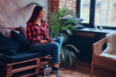 Pazen tişört ve kot bir kanepede oturan sevimli esmer