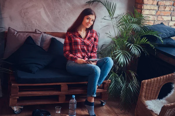 フランネル シャツとジーンズ ソファに座っての魅力的なブルネット — ストック写真
