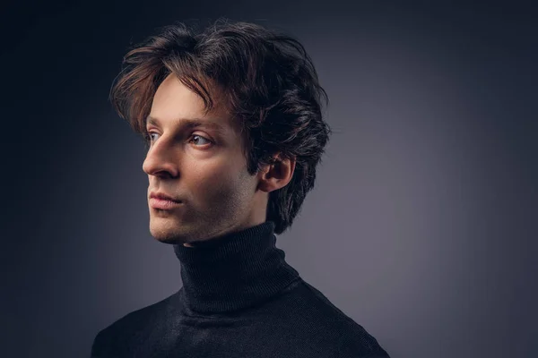 Portrait of a charismatic sensual male in black sweater. Creative personality. Isolated on a dark background.