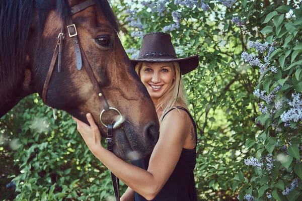 Okouzlující Krásná Blondýna Sobě Černé Šaty Klobouk Objímání Koně Květné — Stock fotografie