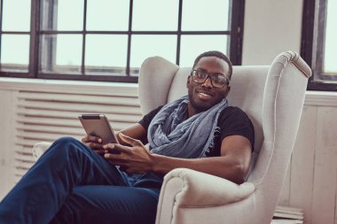 Genç bir öğrenci bir sandalye ve bir tablet kullanarak oturur.