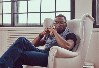 Genç bir Afrikalı-Amerikalı öğrenci bir oda bir sandalyede oturur.