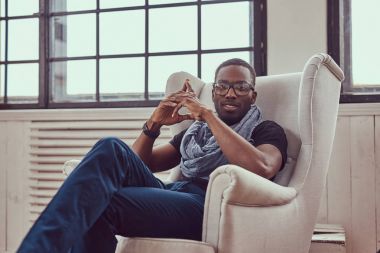 Genç bir Afrikalı-Amerikalı öğrenci bir oda bir sandalyede oturur.