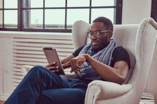 Genç bir öğrenci bir sandalye ve bir tablet kullanarak oturur.