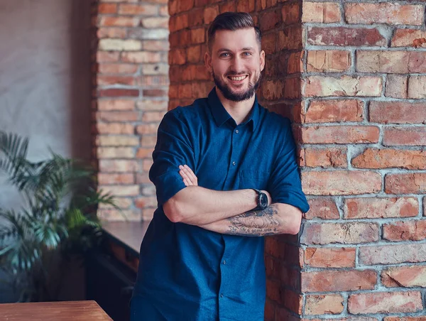 Onun kol ayakta çatı iç ile bir odada bir dövme ile mutlu yakışıklı erkek.