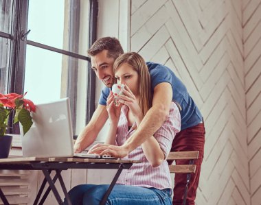 Bir dizüstü bilgisayar ile bir pencerede çalışan iki genç öğrenciler.