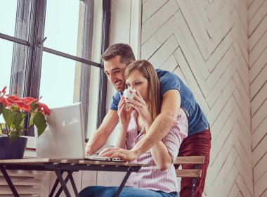 Bir dizüstü bilgisayar ile bir pencerede çalışan iki genç öğrenciler.