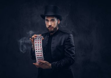 İskambil ve büyü ile hüner karanlık bir arka plan üzerinde duman gösteren sihirbaz siyah takım elbise ve şapka,.