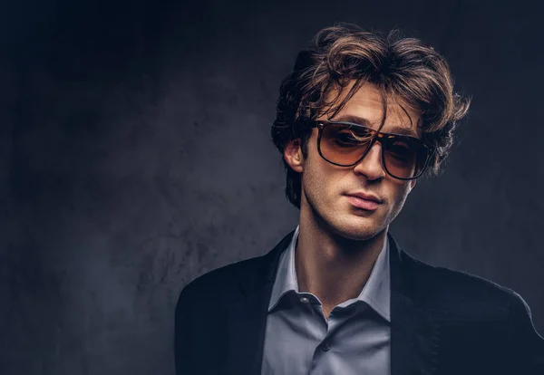 Studio portrait of a charismatic sensual macho with stylish hair and sunglasses