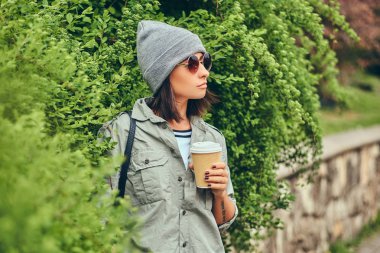 Bir fincan kahve ile bir Şehir Parkı içinde dinlendirici bir esmer hipster portresi.