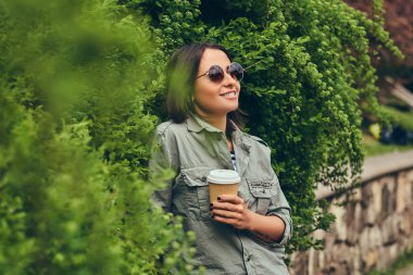 Bir fincan kahve ile bir Şehir Parkı içinde dinlendirici bir esmer hipster portresi.