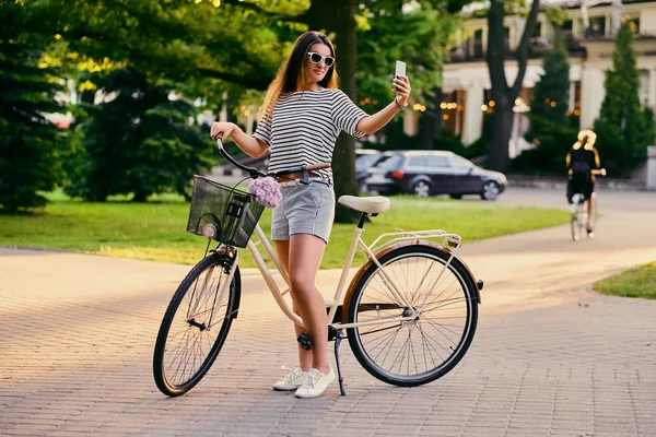 Приваблива брюнетка жінка з велосипедом у міському парку . — стокове фото