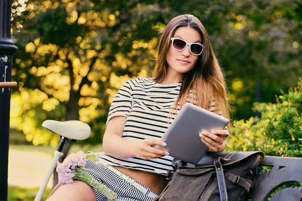 Porträt einer attraktiven Brünette sitzt auf einer Bank mit Fahrrad — Stockfoto