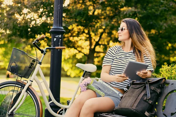 Porträtt av en attraktiv brunett sitter på en bänk med cykel — Stockfoto