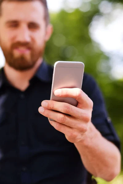 A handsome bearded male tourist in casual clothing using a phone — Stock Photo, Image