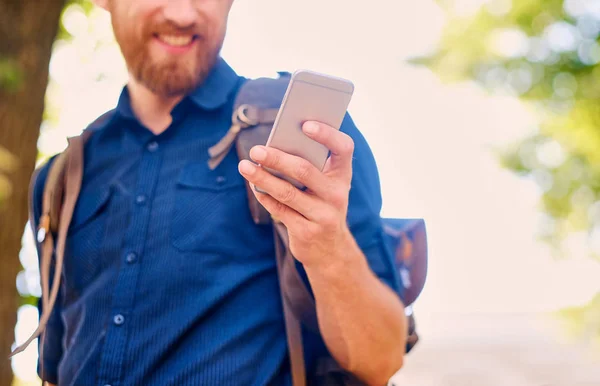 A handsome bearded male tourist in casual clothing using a phone — Stock Photo, Image