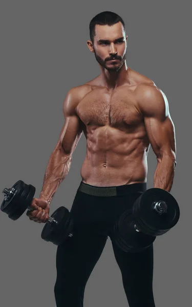 Un tipo musculoso haciendo ejercicio con pesas. Aislado en una ba gris — Foto de Stock