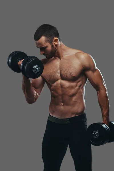 A Muscular guy working out with dumbbells. Isolated on a gray ba — Stock Photo, Image