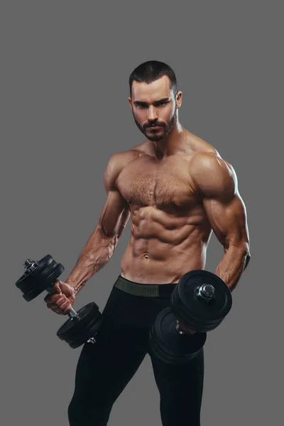 Dumbell ile çalışma dışarı bir kas adam. Üzerinde gri bir ba izole — Stok fotoğraf