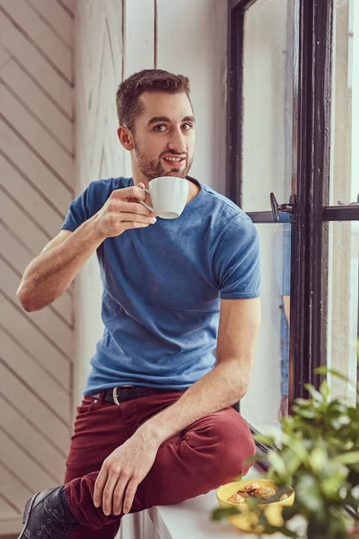 Νεαρός φοιτητής Καυκάσιος πίνει καφέ το πρωί που κάθεται σε ένα windo — Φωτογραφία Αρχείου
