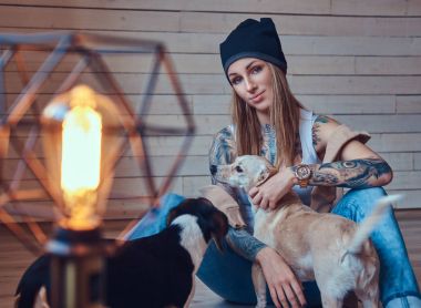 Şık bir tişört ve kot pantolonla köpeklerini sarışın kadın dövme